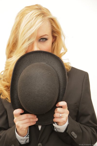 Blonde pornstar Kayden Kross posing in a suit and with a hat at home Gallery Cover Image